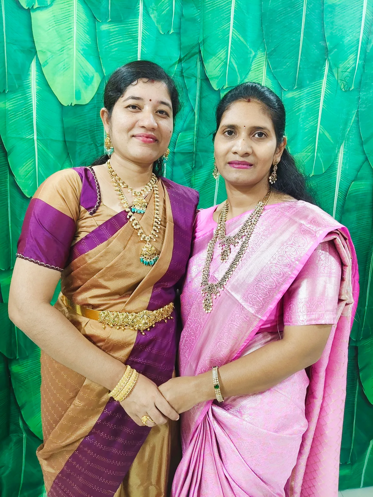 Two women wearing Vasu World 1 gram gold necklaces, bangles and a waist belt